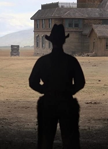 A cowboy wearing chaps rides through a valley