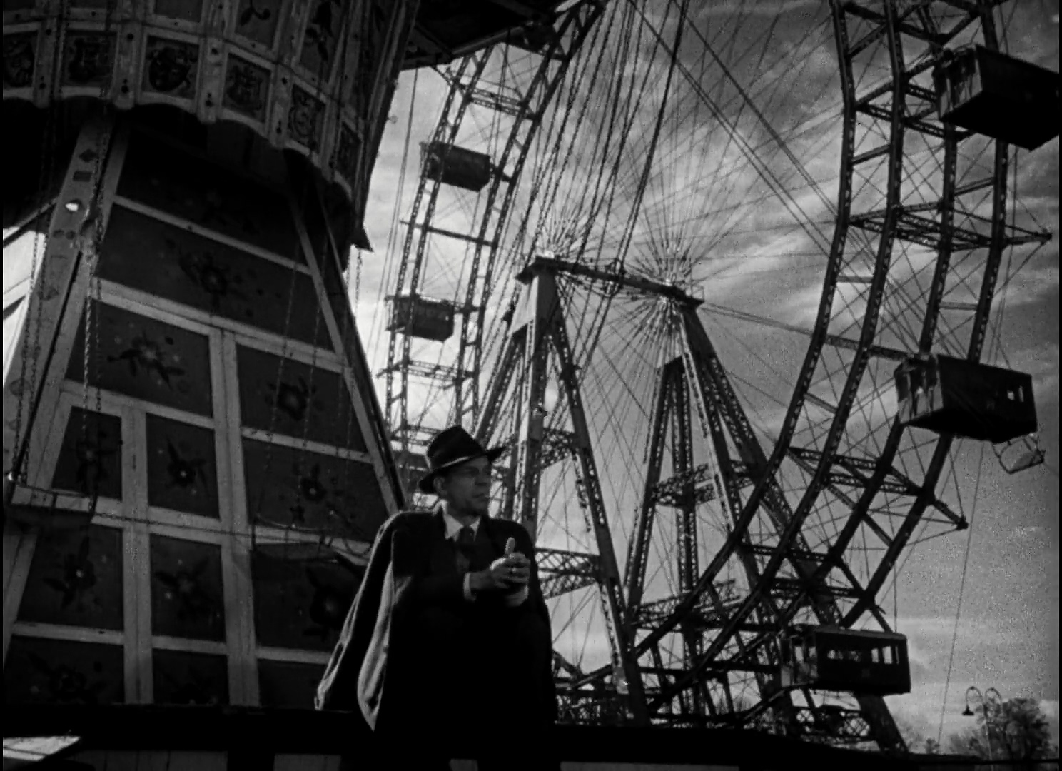 A man stands in front of a ferris wheel