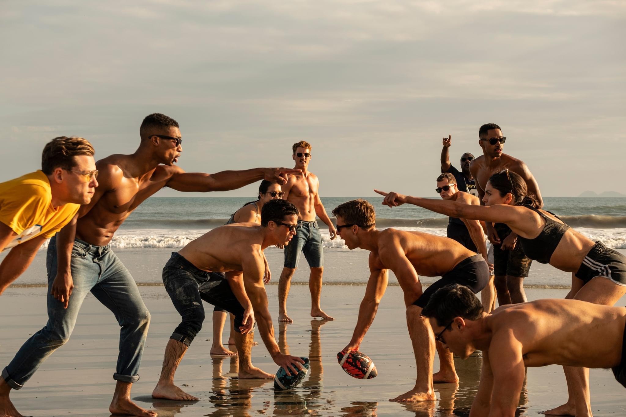 Half naked people playing footy on the beach